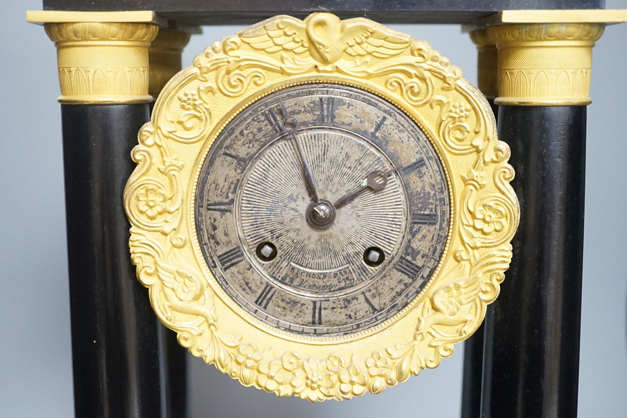 A 19th century French ebonised portico mantel clock with brass mounts, 47 cms high.